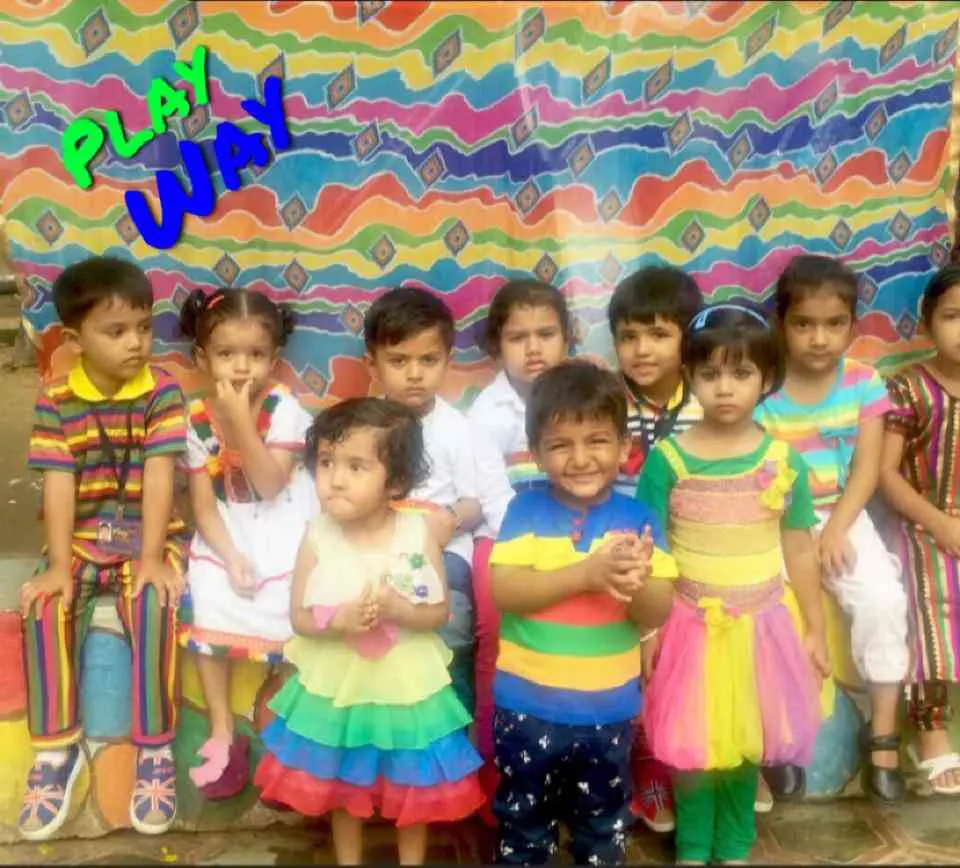 Children in bright clothes in front of a colourful wall