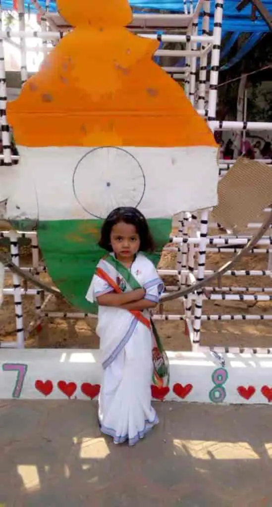 Girl in a white saree in front of a tricolour wall