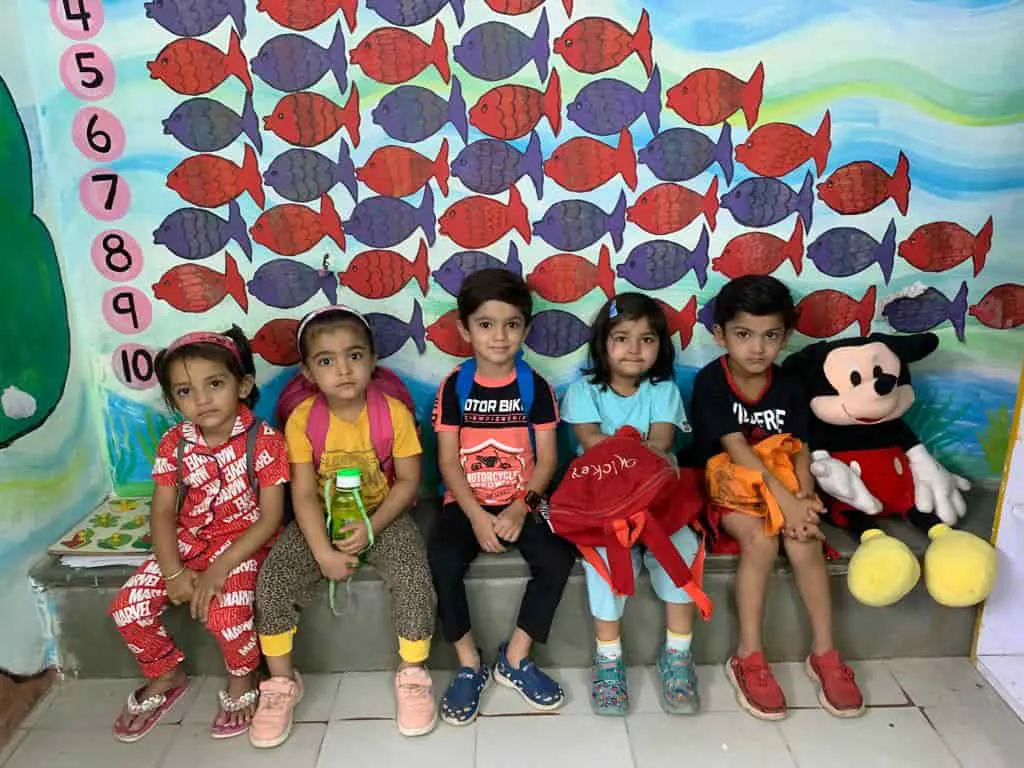 Playway children sitting together in front of a painted fish wall